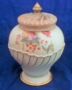 An antique Royal Worcester Porcelain blush ivory pot pourri vase with crown cover and inner lid. The vase is moulded in an shanked ovoid shape number 1720 and is hand painted with flowers by William Hawkins the base with Royal Worcester Company marks and the date code for 1903.