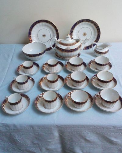 An antique Thomas Grainger Worcester Porcelain tea and coffee service with Hamilton Fluted Tea cups and coffee cans  and fluted new oval shaped teapot decorated with an under glaze blue band with gilded grapevines. Pattern number 195 circa 1810