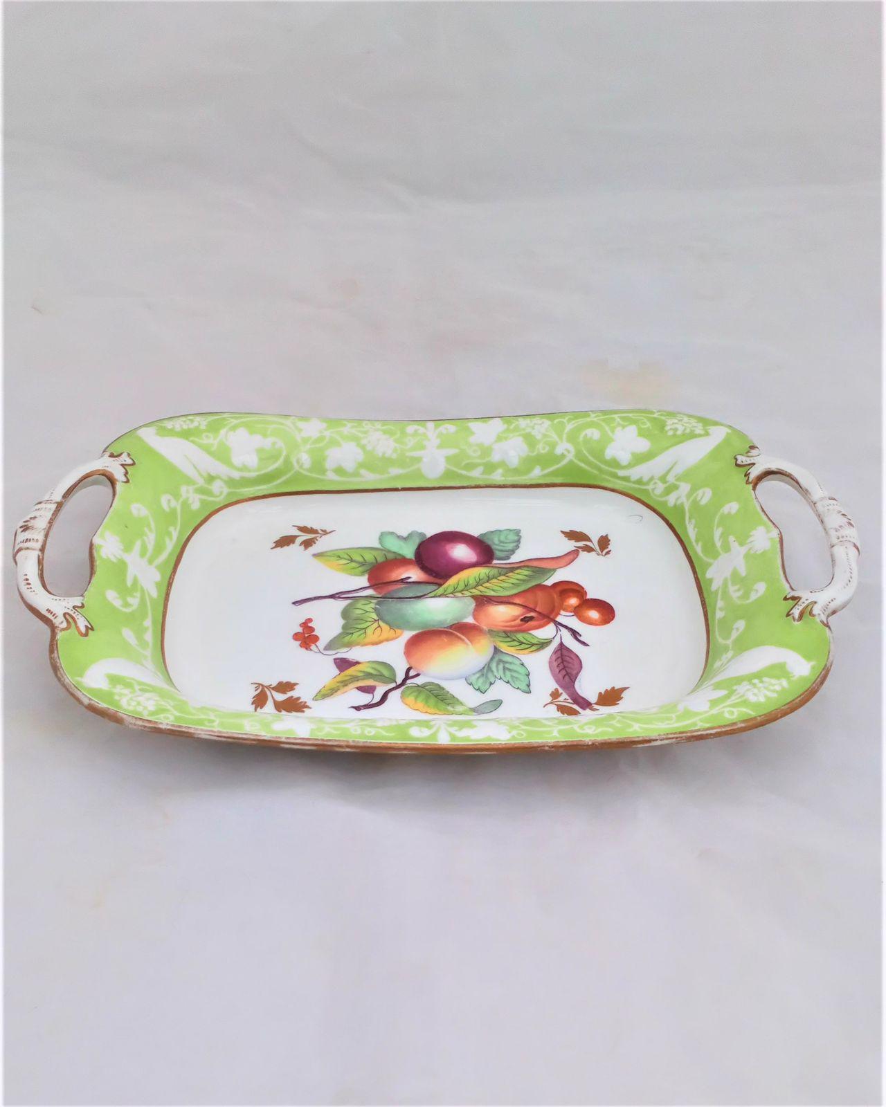 Antique New Hall Porcelain rectangular twin handled dessert dish with low relief rim of birds and fruiting vines on a light green ground. It has a central transfer printed and hand coloured fruit decoration , made in the Georgian period circa 1820 to 1831.