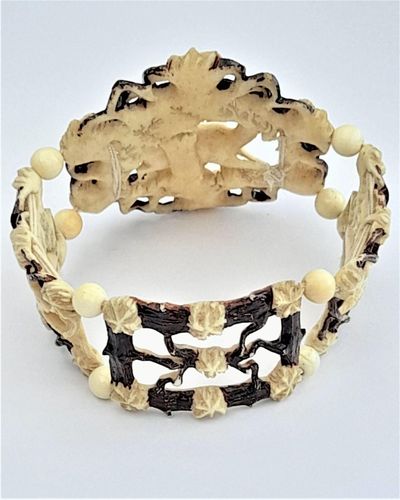 A superb antique hand carved deer antler elasticated panel bracelet with exquisite detail and brown enamel highlighting. The main panels are decorated with deer, the large one with a hart or stag and the sides with seated does. The bracelet dates from the middle of the 19th century in the Victorian period circa 1850. Probably carved in the Black Forest region.