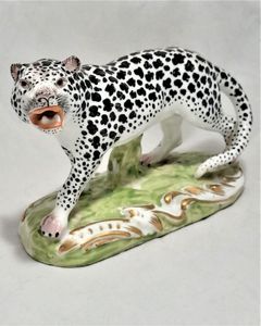 An antique 19th century porcelain Snow Leopard figurine realistically modelled and painted on a green and gilded enamel base probably French by Edme Samson circa 1890