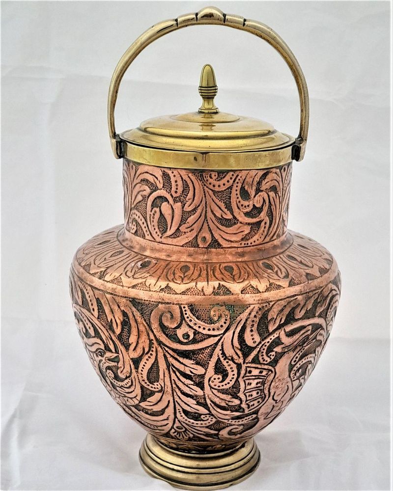 An antique Italian Tuscan repousse copper mezzina water carrier with brass fittings decorated with Cockatrice and acanthus leaf scrolls in an Arts and Crafts style circa 1900
