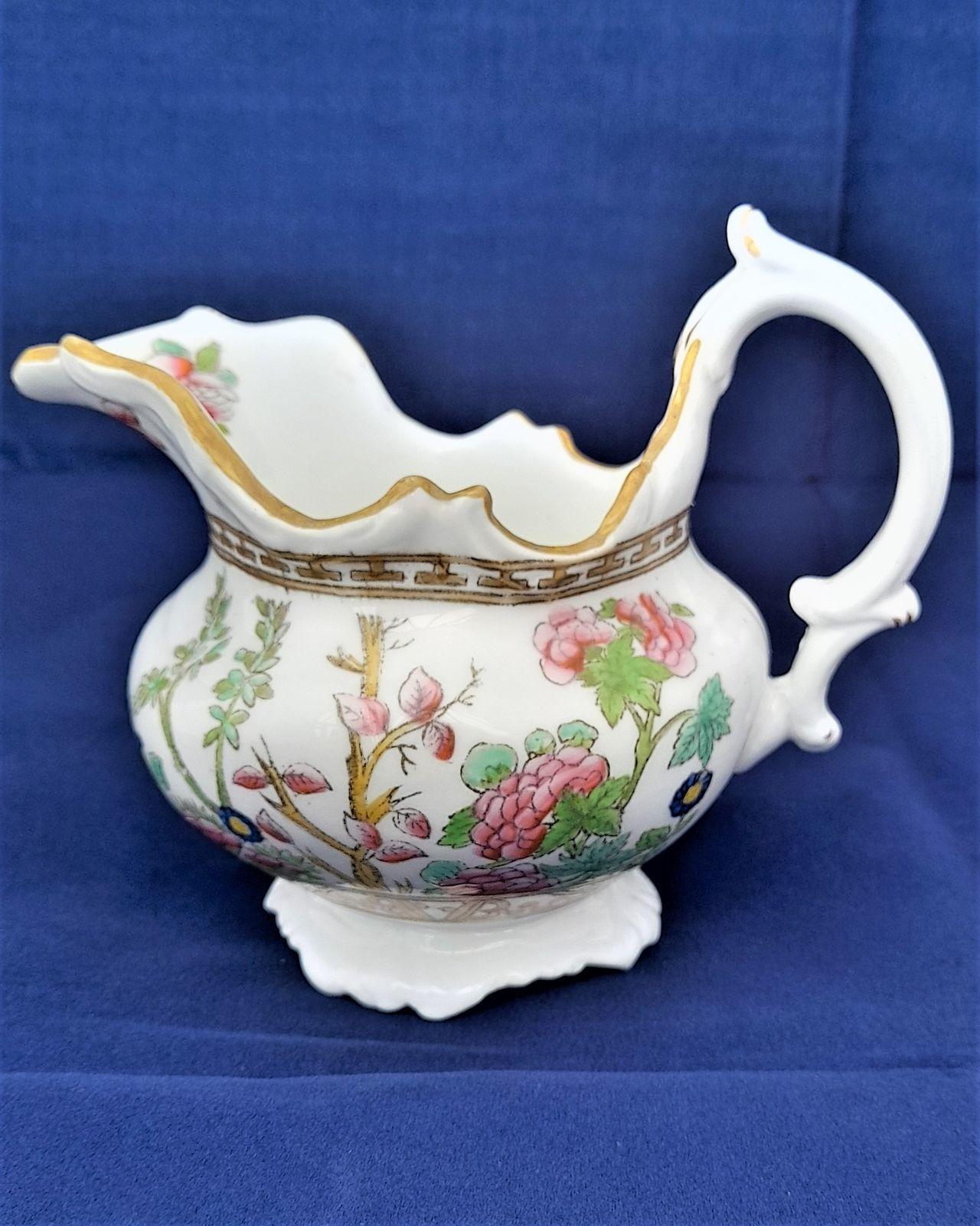 An antique John Rose Coalport porcelain creamer or milk jug decorated with a transfer printed and hand coloured Indian Tree Pattern.  Antique circa 1836 Made in a squat melon shape with a moulded scroll edge and quadrate base. The jug has a composite "C" scroll handle.with thumb rest.