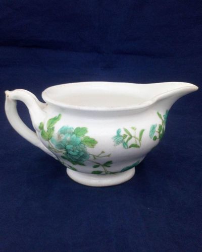 Antique low round porcelain creamer or milk jug made by John Rose of  Coalport Porcelain Works with transfer printed and hand coloured turquoise and green flowers pattern. Dates to circa 1820.
