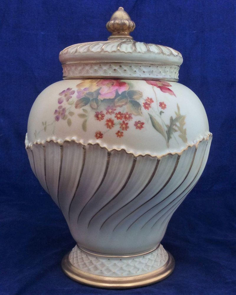 An antique Royal Worcester Porcelain blush ivory pot pourri vase with crown cover and inner lid. The vase is moulded in an shanked ovoid shape number 1720 and is hand painted with flowers by William Hawkins the base with Royal Worcester Company marks and the date code for 1903.
