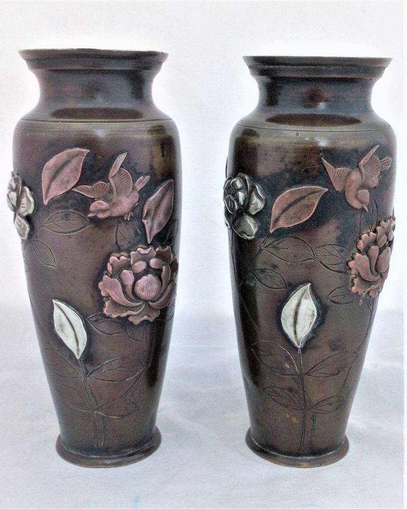 A pair of antique Japanese patinated bronze vases decorated with applied mixed metal birds and peony flowers made in the Meiji period circa 1900.  each 6 inches high and 2.5 inches diameter.