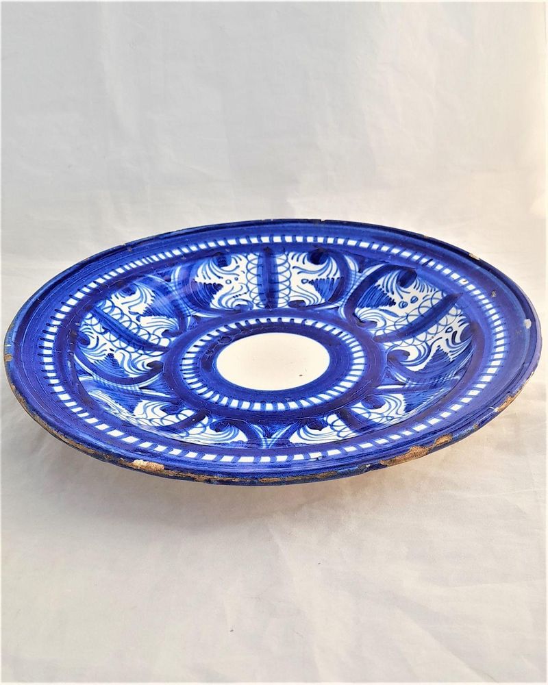 An antique Spanish blue and white tin glazed earthenware faience large round plate dish or charger hand painted in cobalt blue in folk art style based upon Hispano Moresque designs - made in Manises near Valencia in Spain 19th century circa 1850 to 1900. 31 cm diameter 4 cm high
