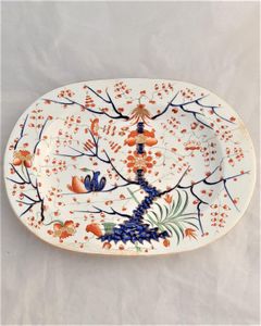 An antique Derby Porcelain Regency period  small platter circa 1815, decorated in the hand painted Formal Lotus Tree pattern. This design is a Japanese Kakiemon style in Imari palette also may be known as the two birds in a tree pattern. 11 inches long  with hand painted iron red crowned crossed batons mark and decorators number 28 and pattern number 49.