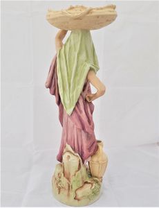 An antique Royal Dux Porcelain Figurine of a female eastern water carrier model number 651 circa 1910.The figure has the very pleasing, muted colour palette of Royal Dux of this period and accentuated with soft gilding. Applied Pink Triangle mark.