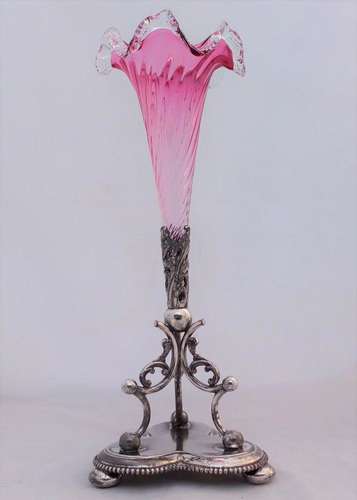 An antique James Deakin and sons silver plated epergne stand with a floriate scroll base and wrythen and frilled ruby glass trumpet circa 1890