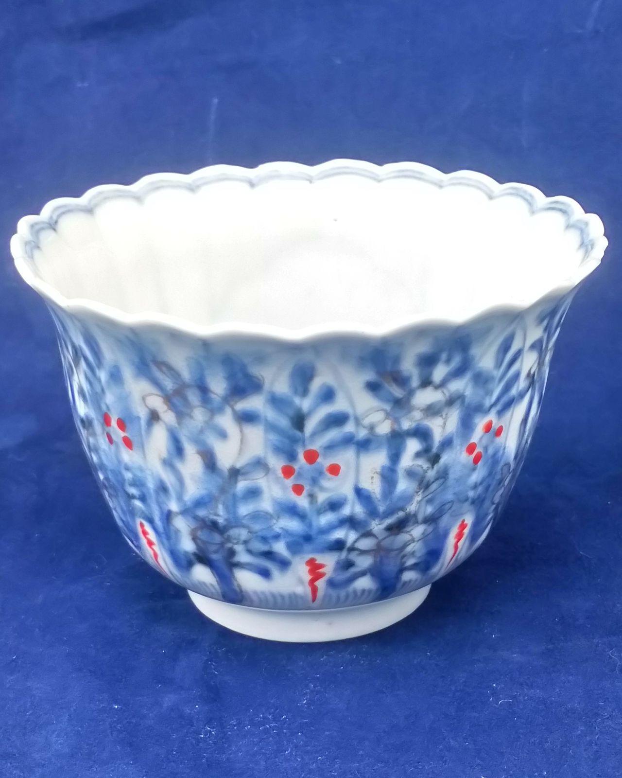 An antique Japanese Hirado porcelain tea bowl or sake cup decorated in under glaze blue and overglaze enamel and gilding with a flowers and grasses pattern. The body is ribbed and the rim scalloped made in the late Edo period marked Zoshuntei Sanpo Zo circa 1860