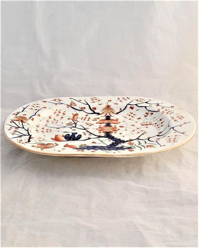 An antique Derby Porcelain Regency period  small platter circa 1815, decorated in the hand painted Formal Lotus Tree pattern. This design is a Japanese Kakiemon style in Imari palette also may be known as the two birds in a tree pattern. 11 inches long  with hand painted iron red crowned crossed batons mark and decorators number 28 and pattern number 49.
