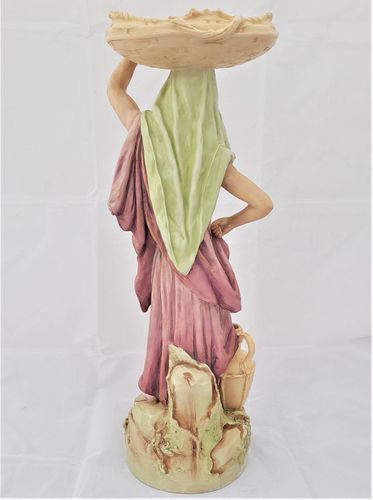 An antique Royal Dux Porcelain Figurine of a female eastern water carrier model number 651 circa 1910.The figure has the very pleasing, muted colour palette of Royal Dux of this period and accentuated with soft gilding. Applied Pink Triangle mark.