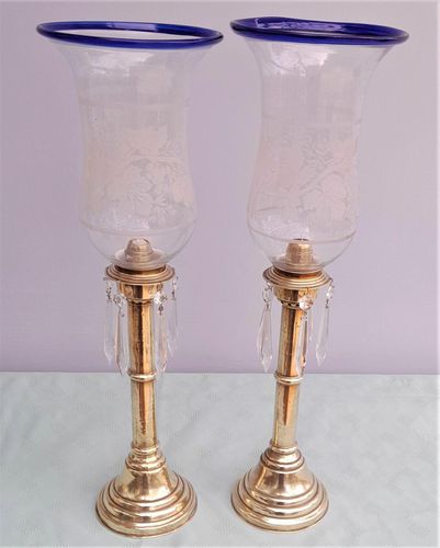 Pair of antique brass spring loaded hurricane candlesticks with grapevine etched glass shades with blue rim & cut glass prism lustre droppers 53 cm High 3.8 kg