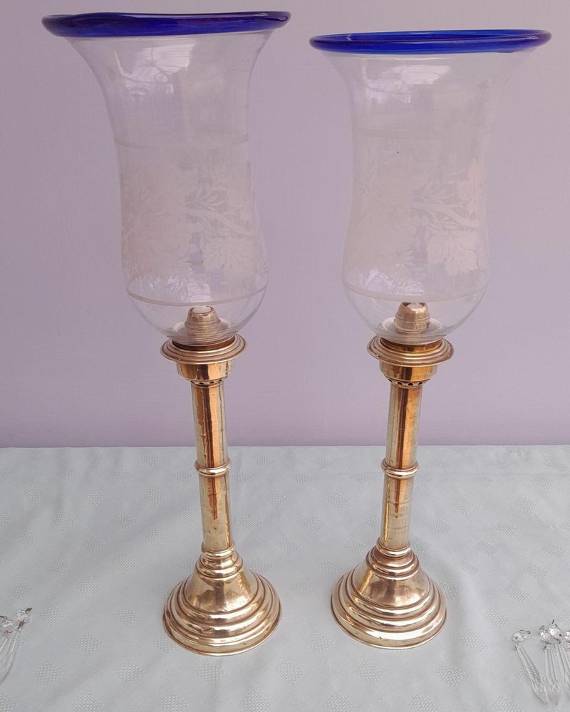 Pair of antique brass spring loaded hurricane candlesticks with grapevine etched glass shades with blue rim & cut glass prism lustre droppers 53 cm High 3.8 kg