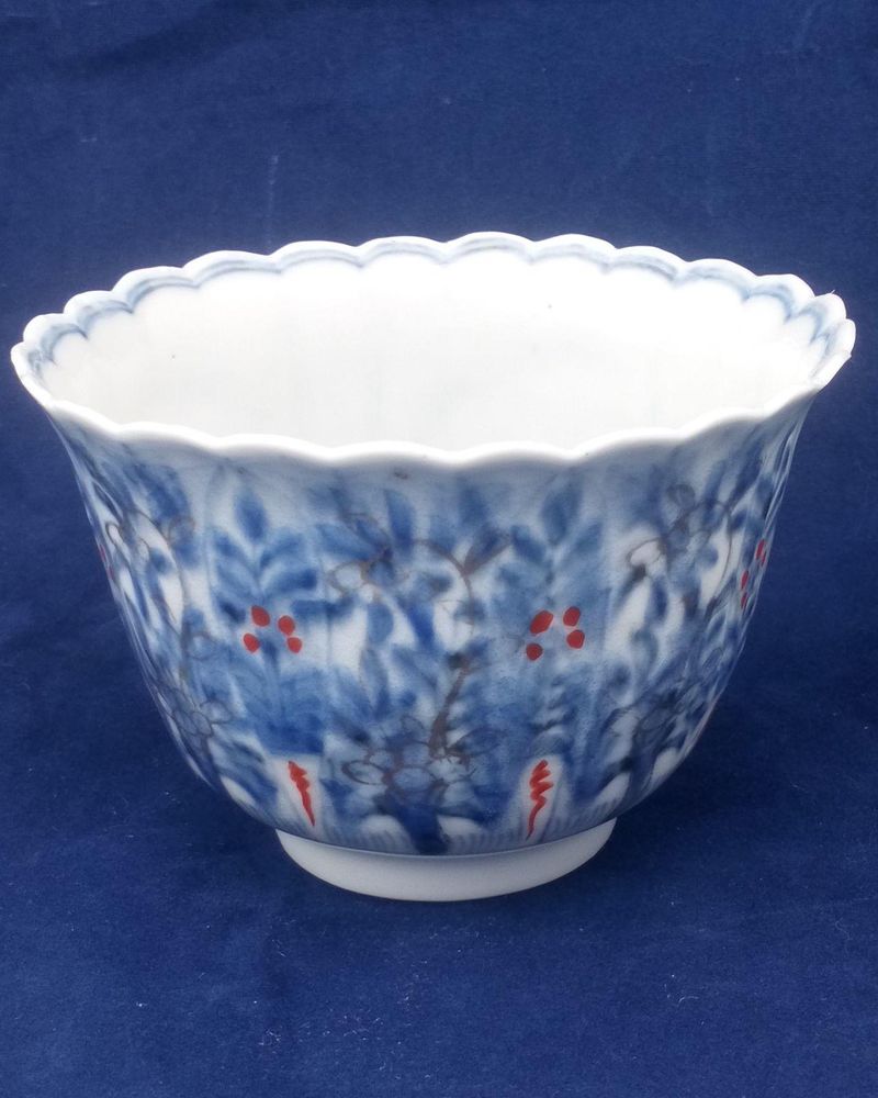 An antique Japanese Hirado porcelain tea bowl or sake cup decorated in under glaze blue and overglaze enamel and gilding with a flowers and grasses pattern. The body is ribbed and the rim scalloped made in the late Edo period marked Zoshuntei Sanpo Zo circa 1860