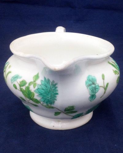 Antique low round porcelain creamer or milk jug made by John Rose of  Coalport Porcelain Works with transfer printed and hand coloured turquoise and green flowers pattern. Dates to circa 1820.