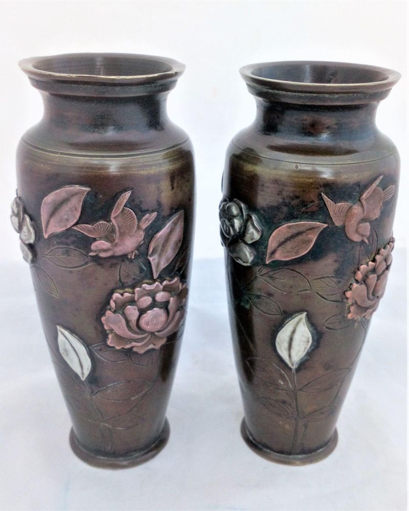 A pair of antique Japanese patinated bronze vases decorated with applied mixed metal birds and peony flowers made in the Meiji period circa 1900.  each 6 inches high and 2.5 inches diameter.