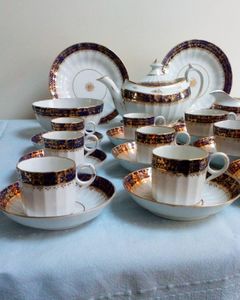 An antique Thomas Grainger Worcester Porcelain tea and coffee service with Hamilton Fluted Tea cups and coffee cans  and fluted new oval shaped teapot decorated with an under glaze blue band with gilded grapevines. Pattern number 195 circa 1810