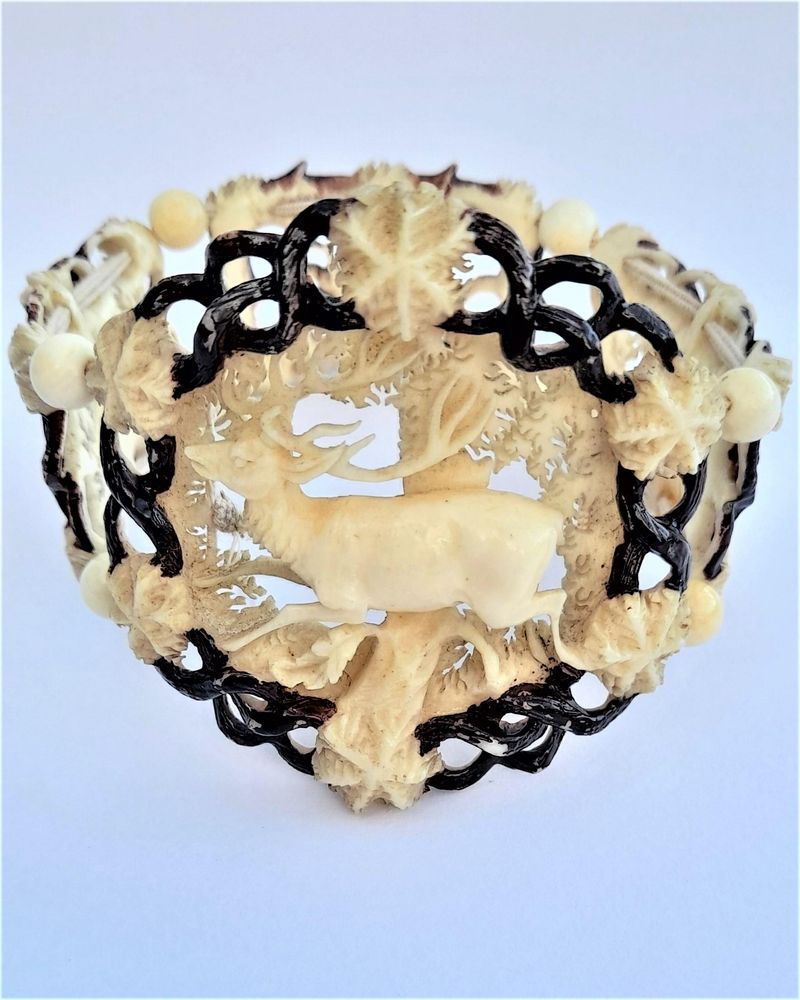 A superb antique hand carved deer antler elasticated panel bracelet with exquisite detail and brown enamel highlighting. The main panels are decorated with deer, the large one with a hart or stag and the sides with seated does. The bracelet dates from the middle of the 19th century in the Victorian period circa 1850. Probably carved in the Black Forest region.