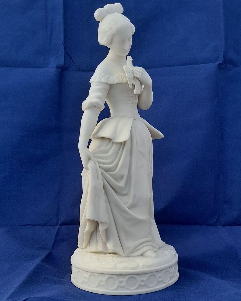An antique Minton white Parian porcelain figurine of a young woman holding a bird symbolic of kindness and innocence circa 1845 29.5 cm high 1 kg in weight some collectors may refer to this as biscuit or bisque porcelain.
