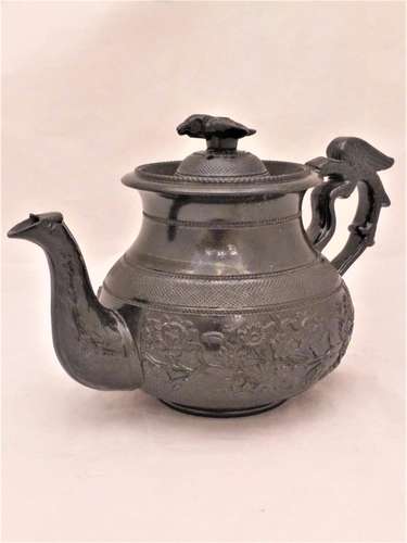 An antique Cyples Egyptian black floral sprigged baluster shaped glazed basalt teapot with an eagle handle and bird finial circa 1830