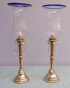 Pair of antique brass spring loaded hurricane candlesticks with grapevine etched glass shades with blue rim & cut glass prism lustre droppers 53 cm High 3.8 kg