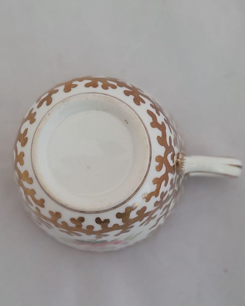 An antique mid Victorian porcelain tea cup and saucer with a scalloped rim and reinforced handle hand painted with roses and gilded extensively with a sea weed pattern made by Sir James Duke & Nephews circa 1860 in the factory previously run by Samuel Alcock and company.