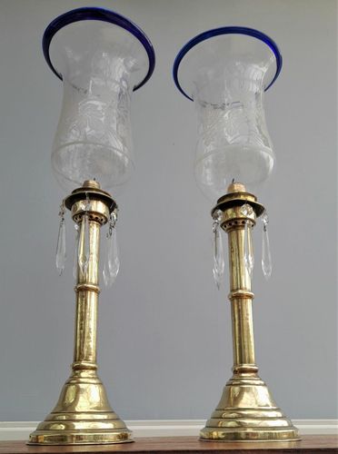 Pair of antique brass spring loaded hurricane candlesticks with grapevine etched glass shades with blue rim & cut glass prism lustre droppers 53 cm High 3.8 kg