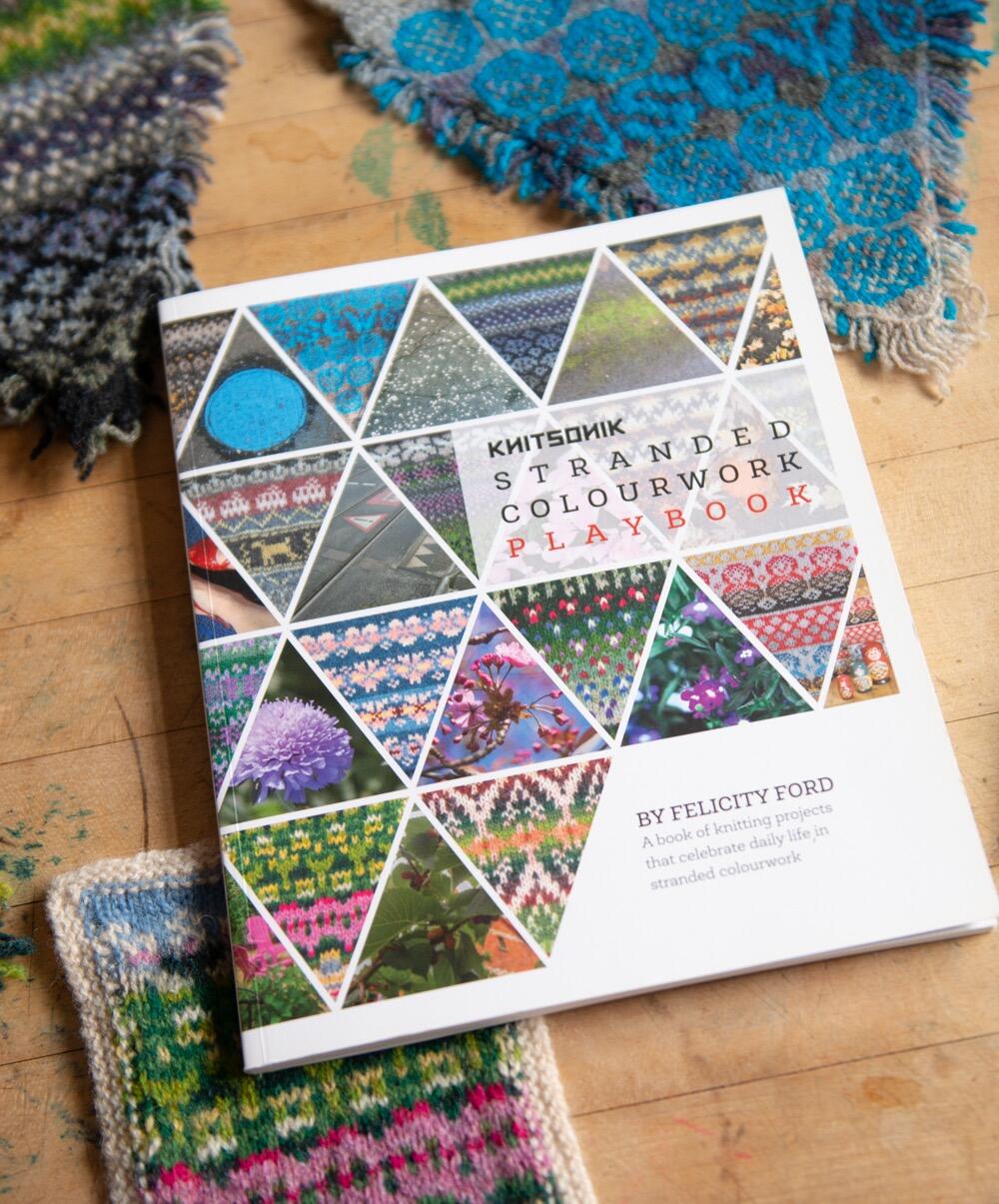 KNITSONIK Stranded Colourwork Playbook lying on a desk, surrounded by some of the same projects that are contained within it
