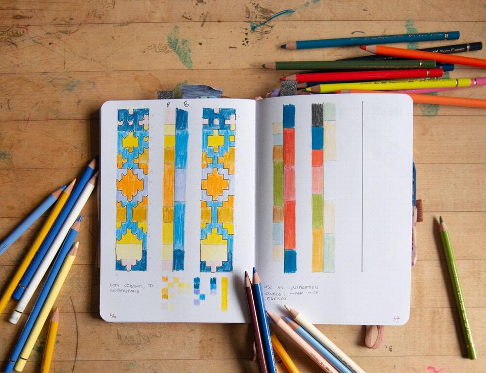 an image of colouring pencils and colouring pages spread out on a wooden table, on which someone is clearly doing some creative colouring-in