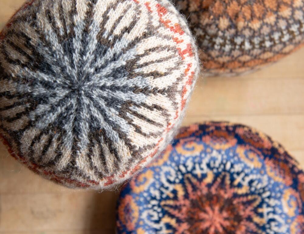 Closeup of three knitted hats; clockwise from top left: Featherheid, Skystone and Shetland Muse