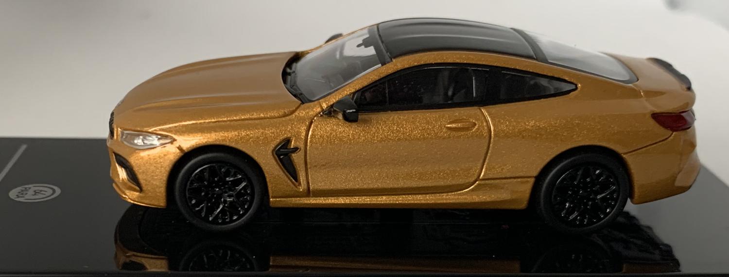 An excellent scale model of a BMW M8 Coupe decorated in ceylon gold with black roof, rear spoiler and black wheels.