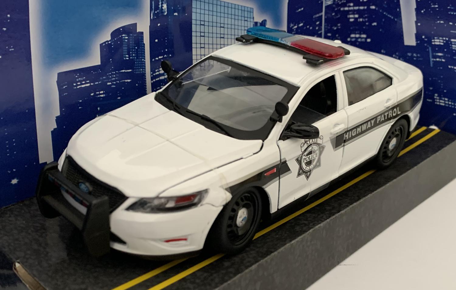 An excellent scale model of a Ford Police Interceptor car decorated in white with authentic graphics, black and silver wheels.