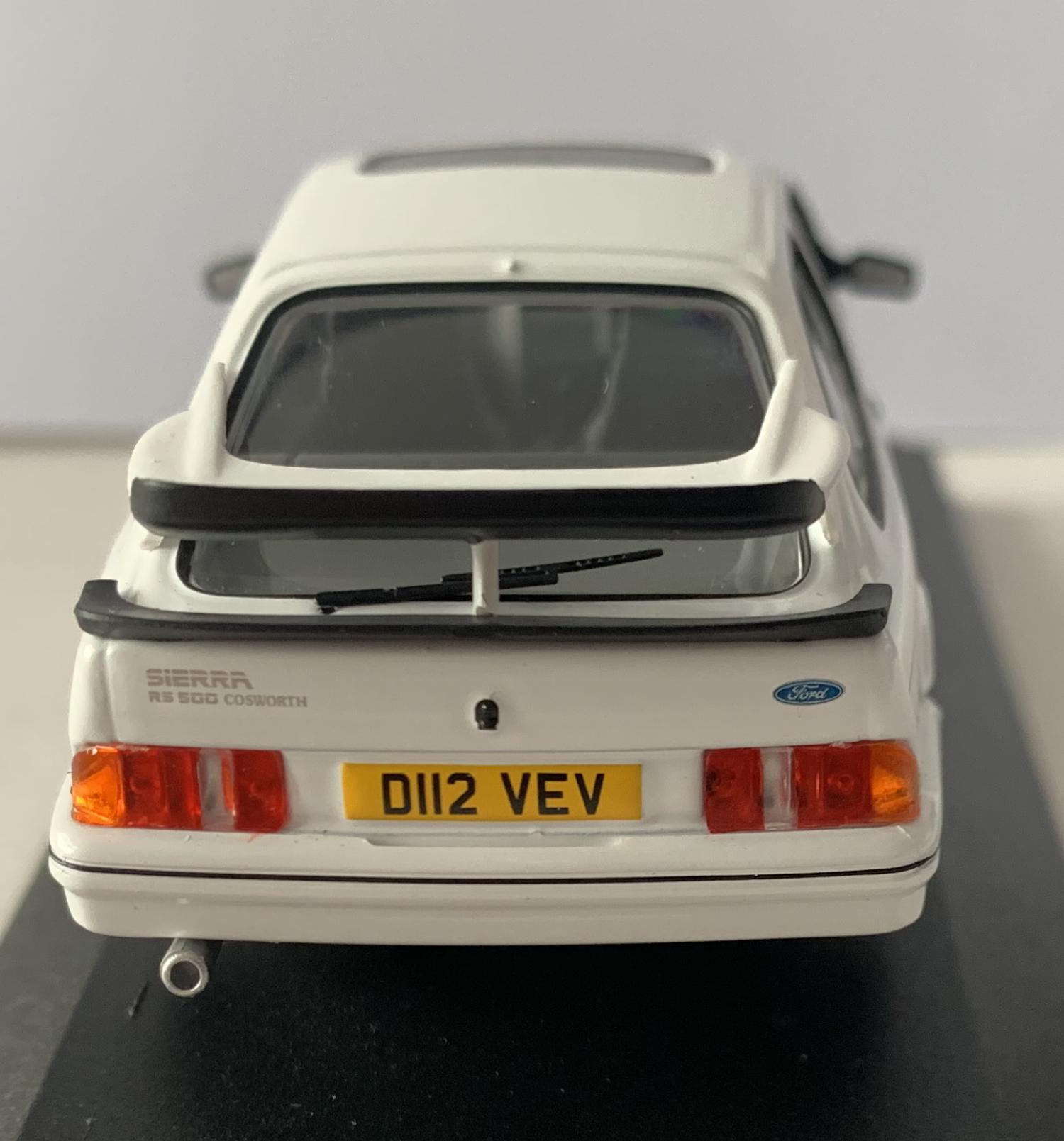 An excellent scale model decorated in diamond white with authentic graphics, rear spoiler, sunroof and silver wheels.  Other trims are finished in black.  The interior is finished in grey with black RHD steering.  Features working wheels.  The Ford badge is finely replicated on the front and extends to the rear with the lettering Sierra RS500 Cosworth.  Model is presented on a removable plinth with a removeable hard plastic cover.  One of a Limited Edition of 1,500 pieces and includes a Limited Edition Collector Card.  Model presented in Corgi Vanguards packaging