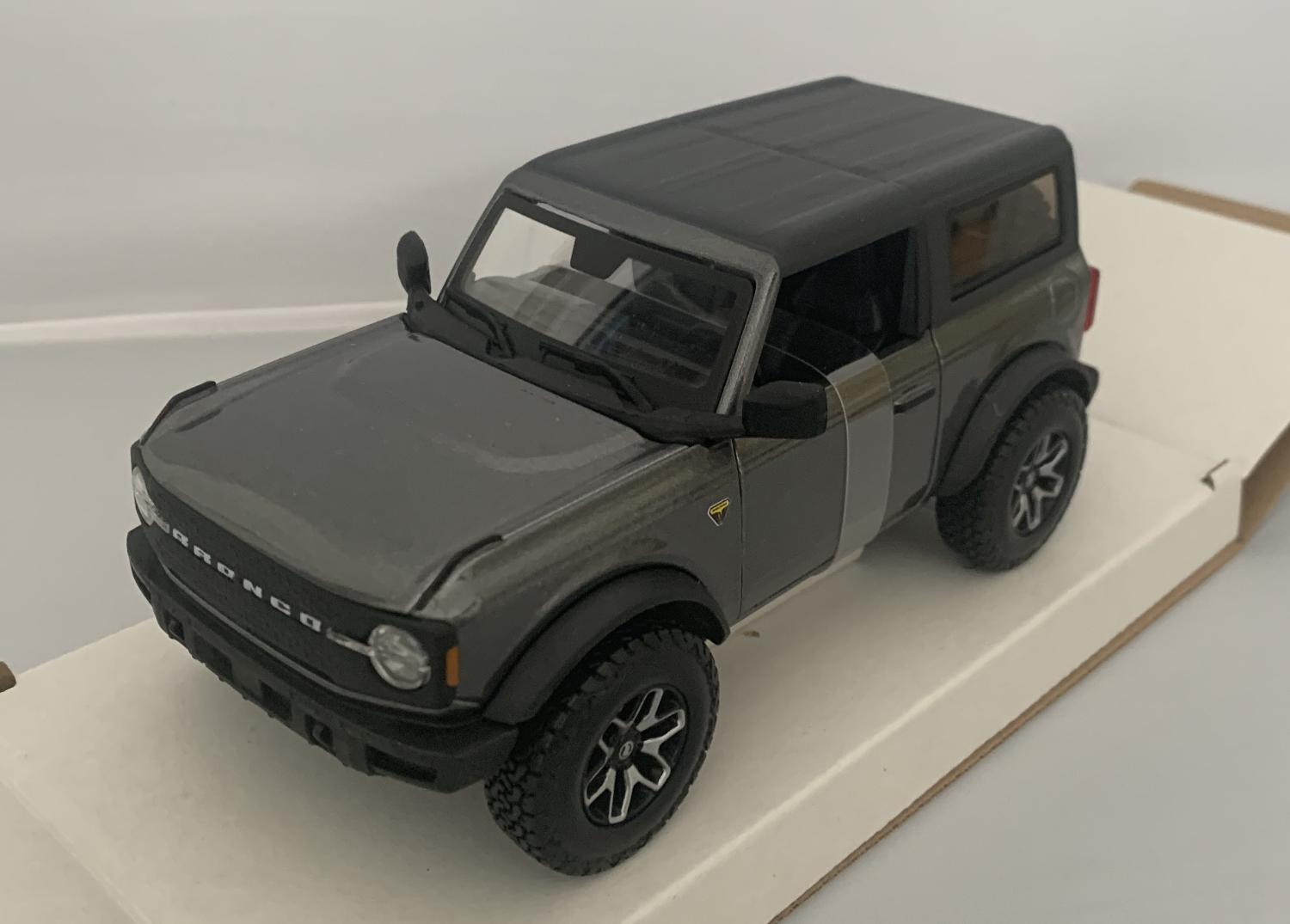 An excellent scale model of a Ford Bronco Badlands decorated in grey and black roof with silver and black wheels. Other trims are finished in black.  Features include opening driver and passenger doors, working wheels and spare wheel on rear door