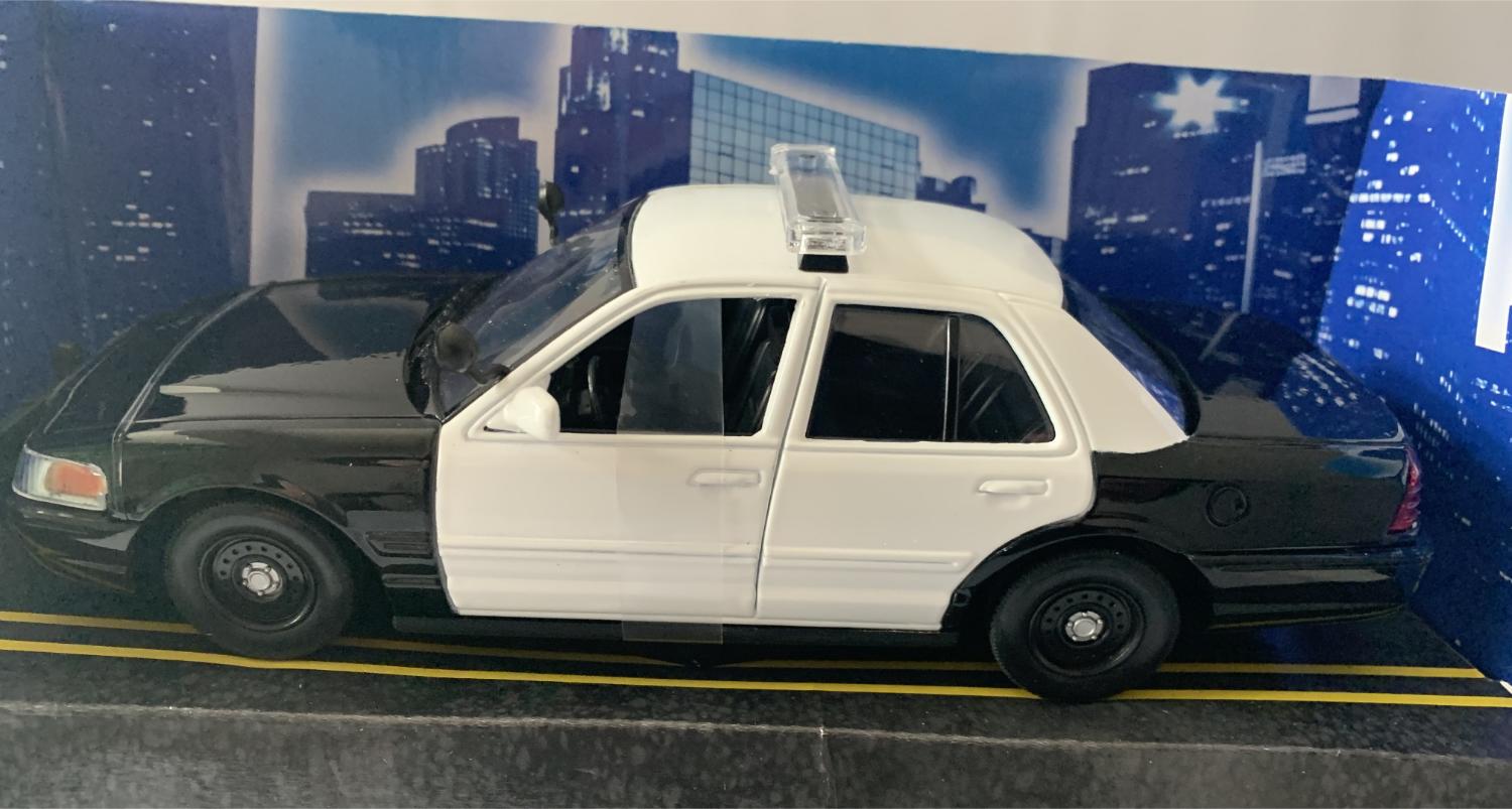 An excellent scale model of a Ford Crown Victoria Police Interceptor car decorated in black and white with black wheels.  Other trims are finished in black