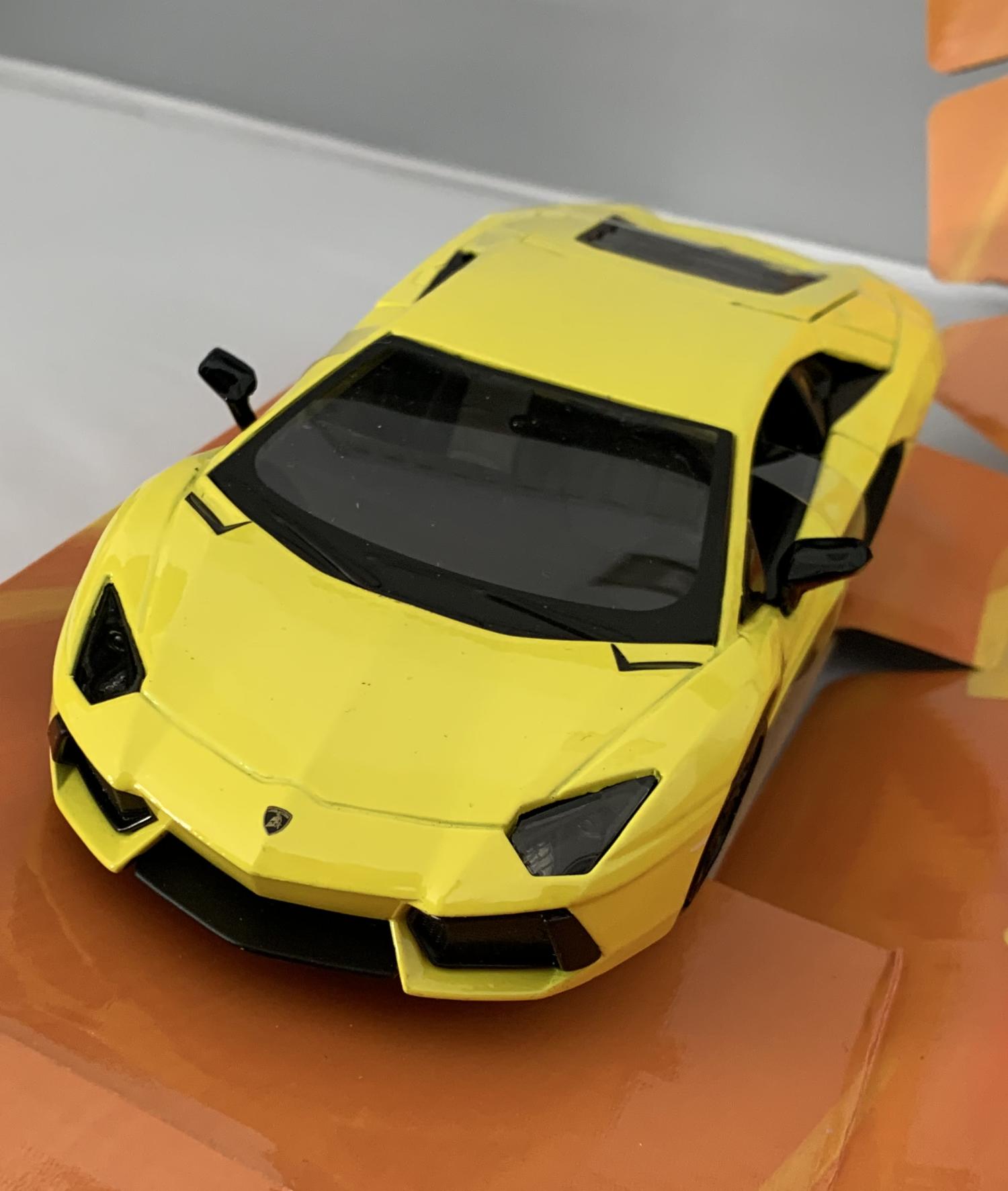 An excellent scale model of a Lamborghini Aventador LP 700-4 decorated in yellow with black wheels.   Features opening driver and passenger doors, opening rear to reveal detailed engine