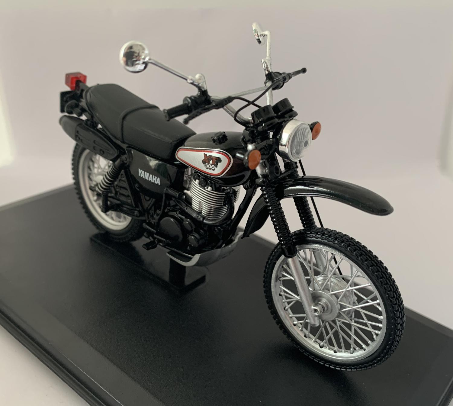 An accurate scale model of a 1988 Yamaha XT 500 decorated in black and silver with authentic graphics and silver spike wheels. Other trims are finished in chrome, black and silver. Features include moveable steering, instrument detail, working stand, rubber rolling wheels and real looking seat.