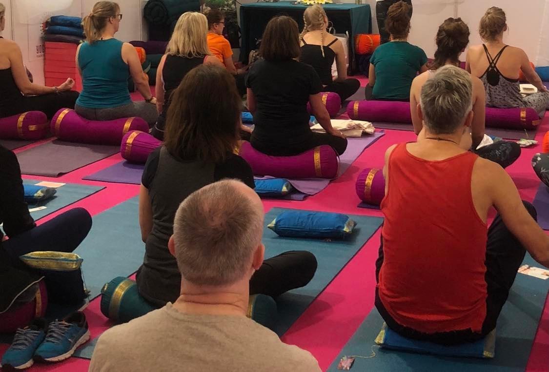 Yoga students sitting on cushions and bolsters