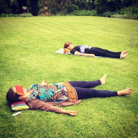 Yoga students in relaxtion lying in a sunny garden