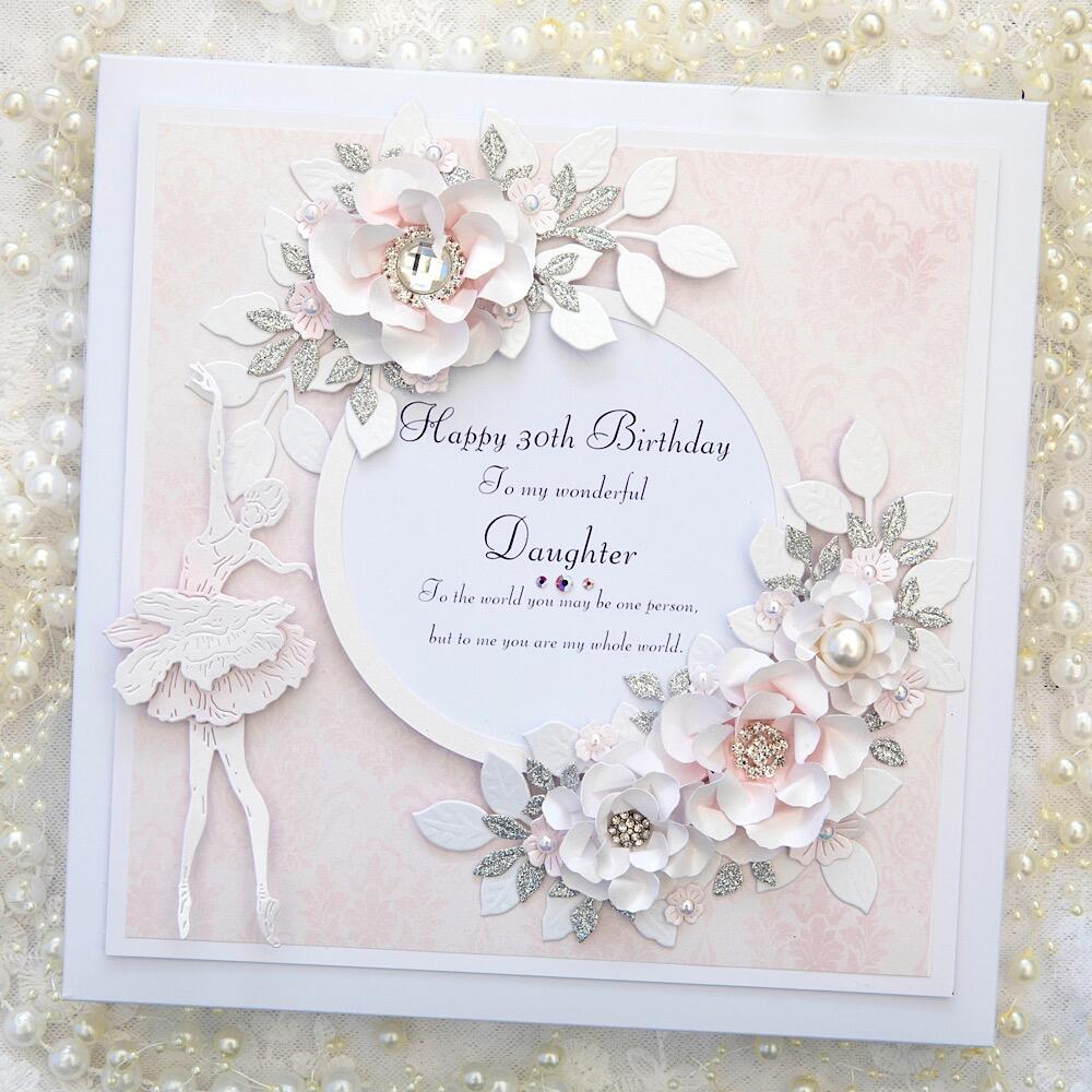 A square greeting card sits against a white lace background covered in ivory and white pearls