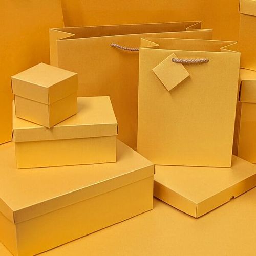 Stacked yellow gold luxury gift boxes and bags with rope handles on display