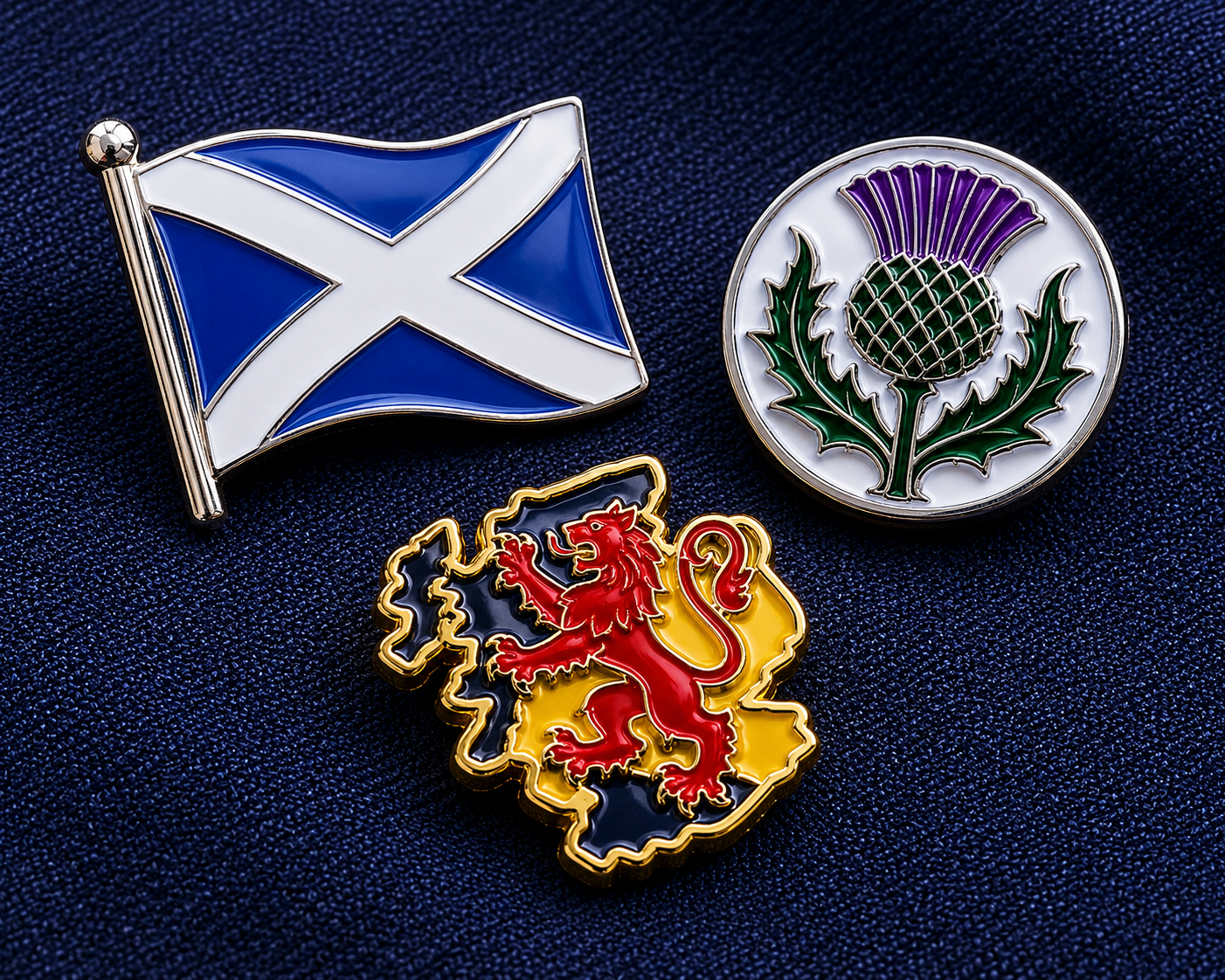 Scottish pin badges including Saltire flag and thistle designs on dark navy fabric