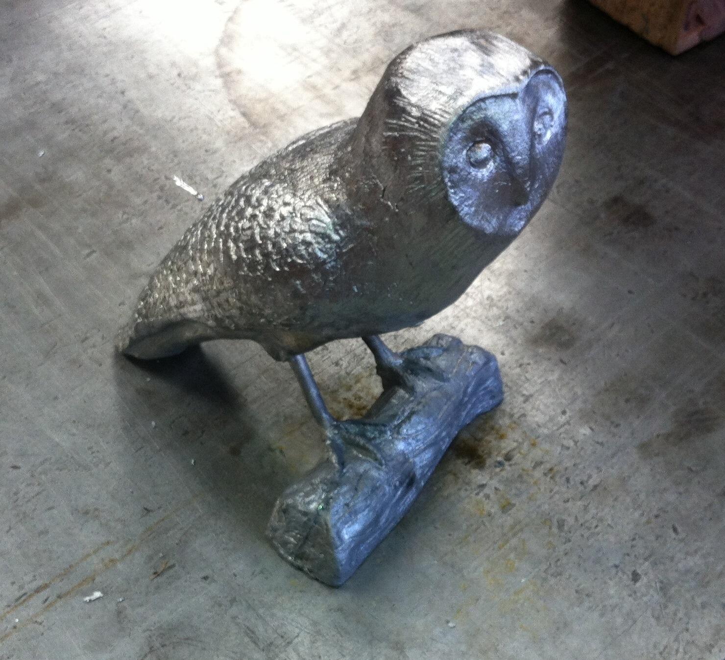 Standing Owl made in lead green bush behind.