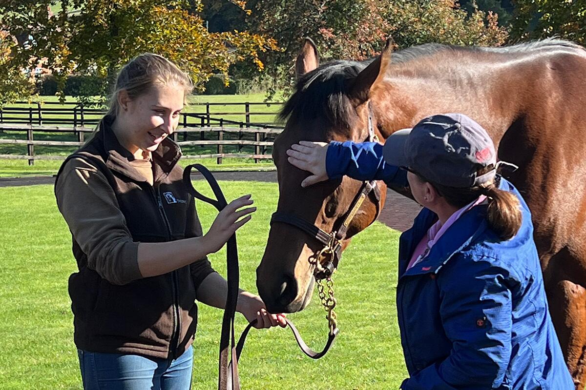 RacehorseClub member patting racehorse at stable day visit