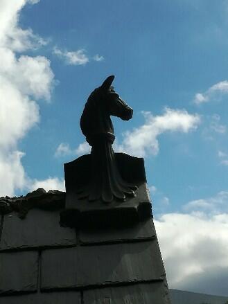 Angled slate grey horse roof finial being installed on gable end roof