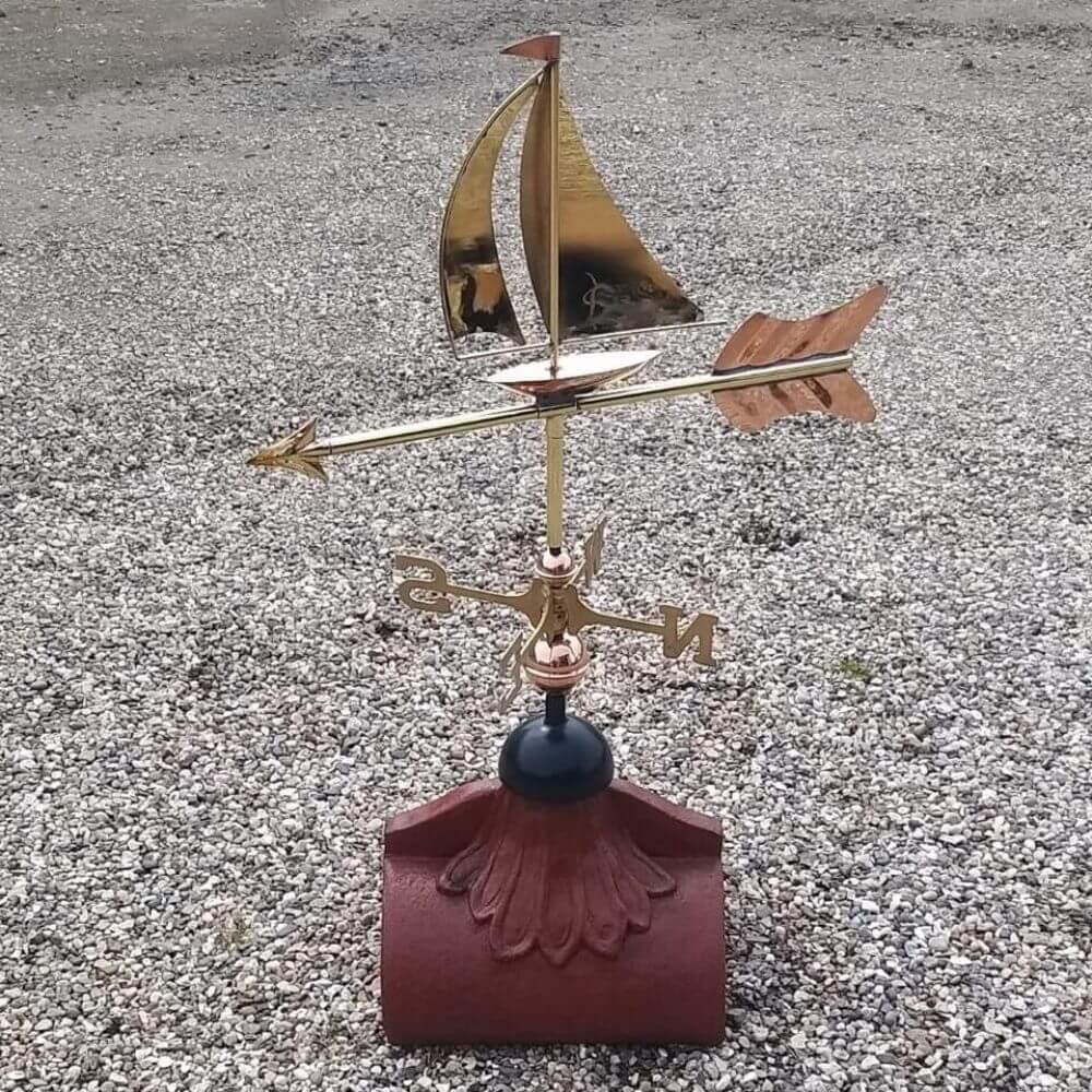 Polished copper sailboat weathervane fitted to a square ridge tile