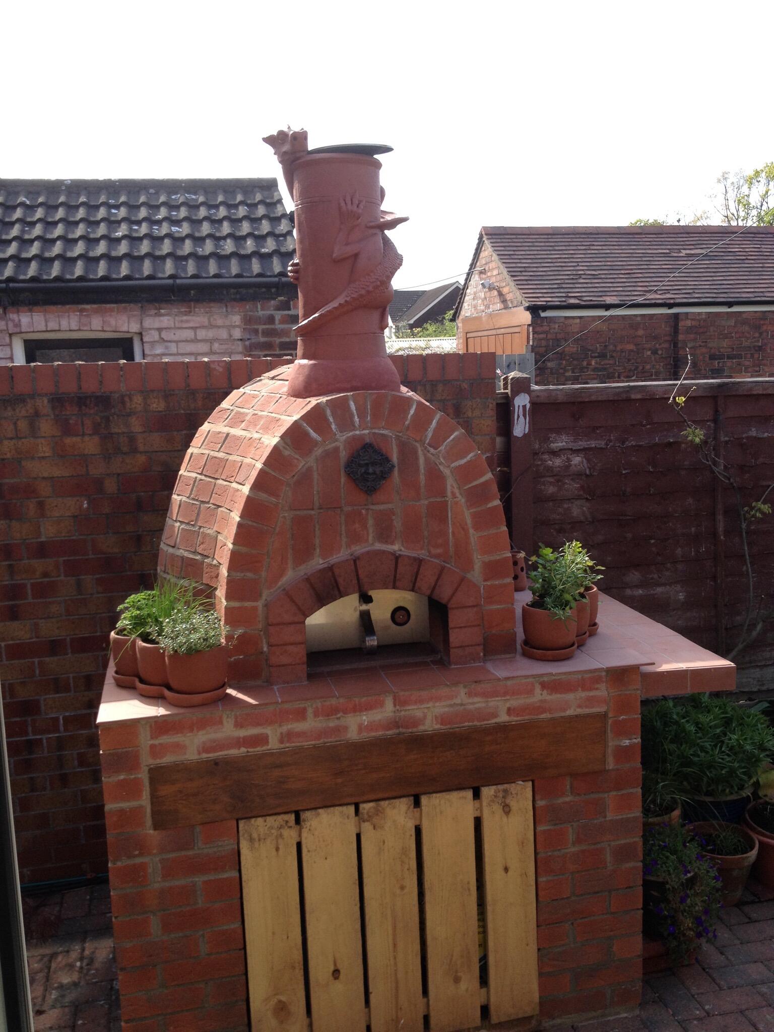 Terracotta dragon chimney pot installed on a brick built pizza oven