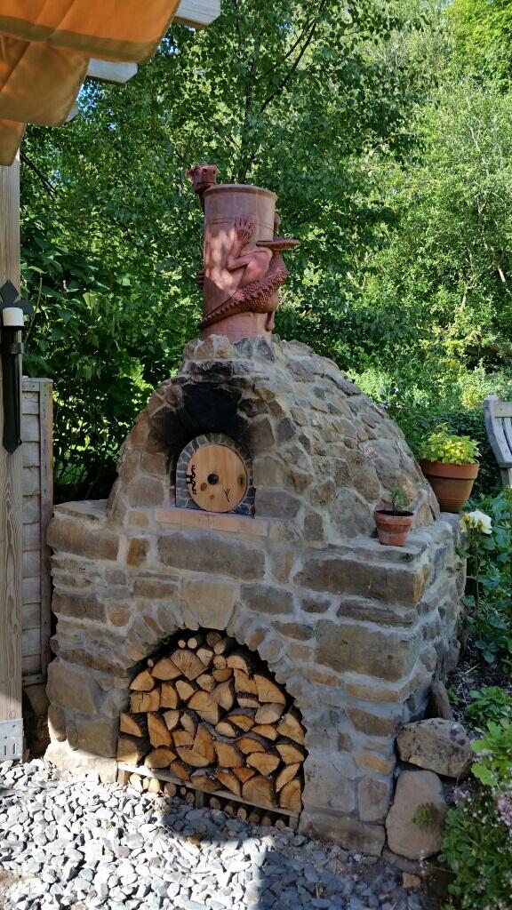 Pizza oven made of stone with a terracotta dragon chimney pot